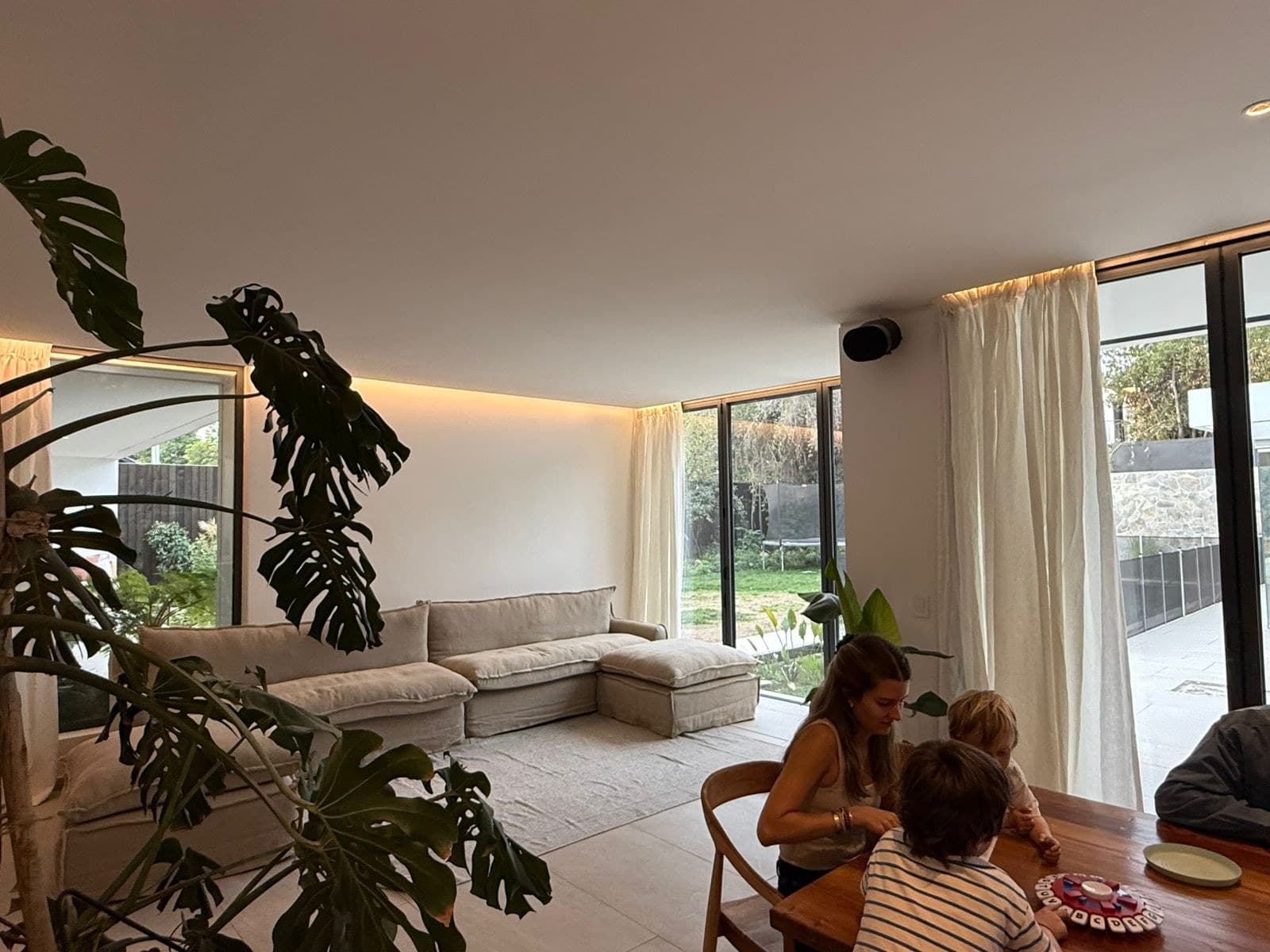 Living en doble altura con cortinas naturales abriéndose al jardín — Casa Fátima