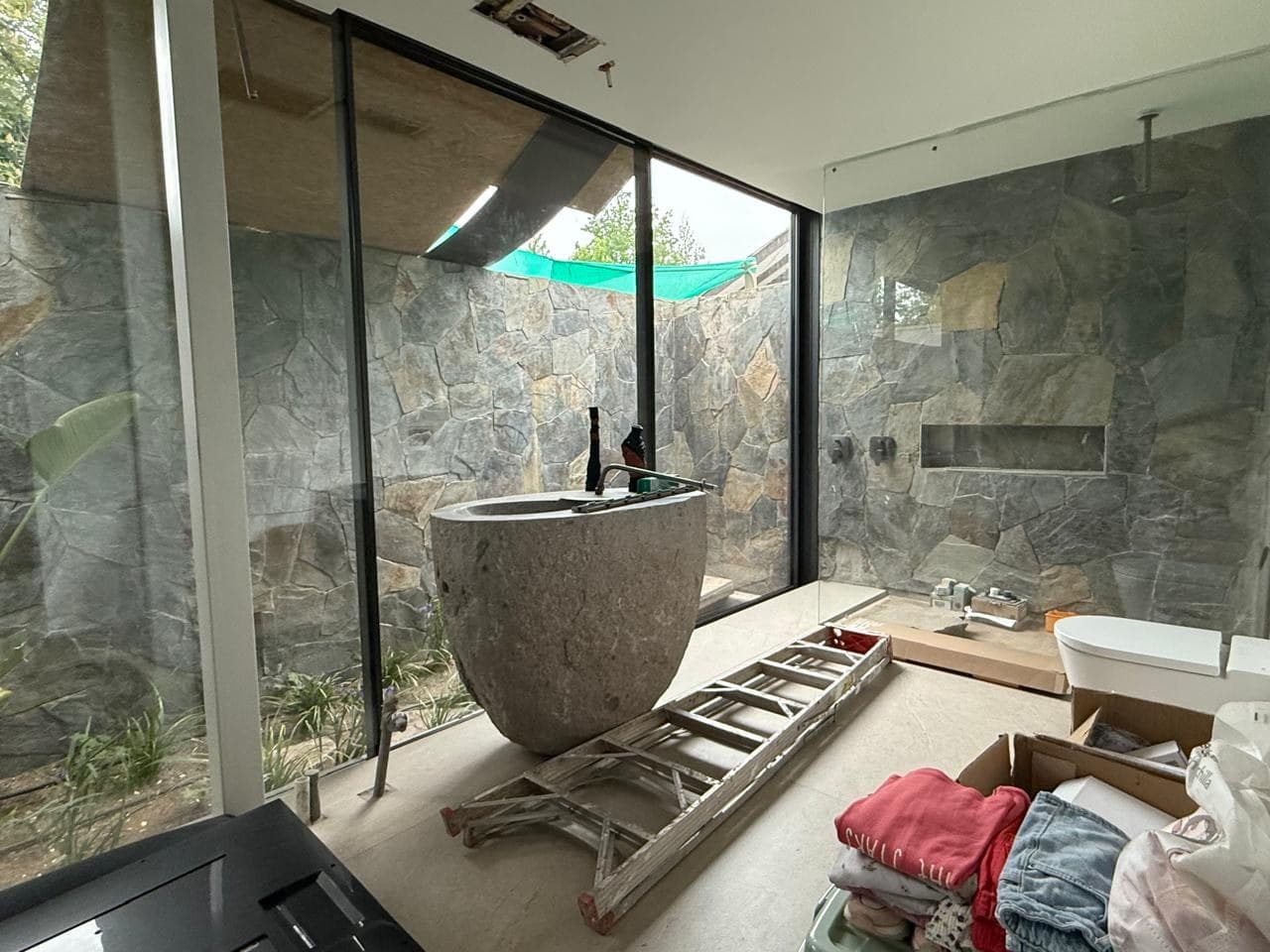 Baño en construcción con tina de piedra labrada y muros de pizarra — Casa Fátima